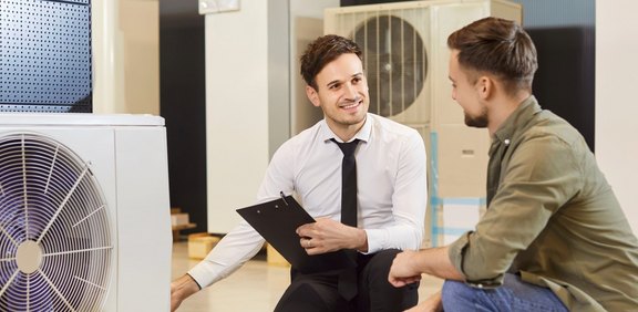 Fachberater bespricht neben Wärmepumpe Details mit Kunde